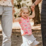 meisje aan handen van ouders